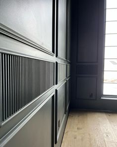 an empty room with wood flooring and black painted walls, next to a window