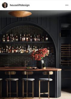 an image of a bar with bottles on the wall and stools in front of it