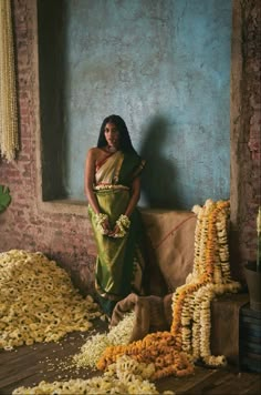 a woman standing next to a pile of flowers