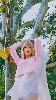 a woman in a pink top and white skirt sitting on a tree branch with her hands behind her head