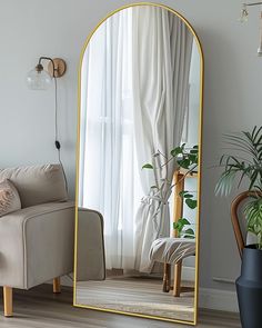 a living room with a couch, chair and large gold mirror in the middle of it