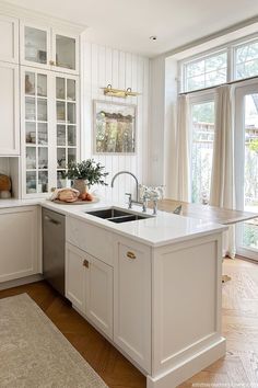 a kitchen with white cabinets and an island in front of a window that is open to the outside