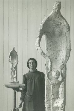 a woman standing in front of a sculpture