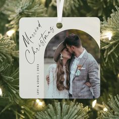 a christmas ornament hanging from a tree with a couple's photo on it