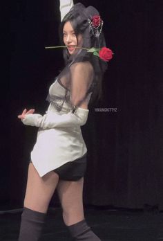 a woman is walking on the runway with a rose in her hair and wearing tight stockings