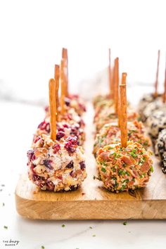 an assortment of appetizers on a wooden board with toothpicks sticking out of them