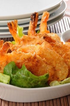 a bowl filled with fried shrimp and lettuce next to dipping sauce on plates