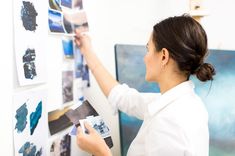 a woman is painting on the wall with blue and white colors in an art studio