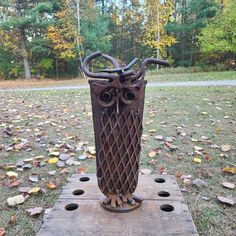 an owl sculpture sitting on top of a piece of wood in the middle of a field