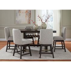 a dining room table with four chairs and a vase on the table in front of it