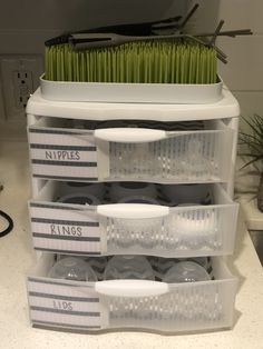 an organized kitchen counter with dishes and utensils in plastic containers on the bottom shelf