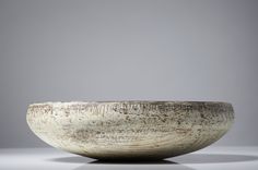 a white bowl sitting on top of a table next to a gray wall and floor