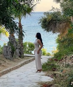 a woman standing on a path near the ocean