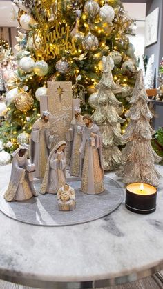 a christmas tree is decorated with gold and silver ornaments, including figurines from the nativity scene