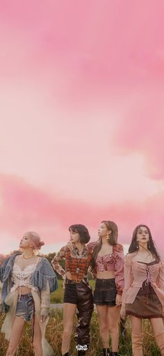 four young women standing in the grass with their arms around each other and looking up into the sky