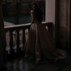 a woman in a long dress standing on a balcony