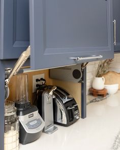 a blender and other kitchen appliances under the cabinet doors in a kitchen with blue cabinets