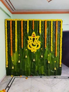 a wall decorated with yellow flowers and hanging bells for ganesh pujamaal