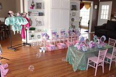 a room filled with tables and chairs covered in pink and green tablecloths next to a black couch