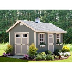 a small gray shed sitting in the middle of a lush green field