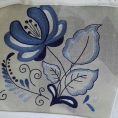 a blue flower is embroidered onto a white cloth with black and gray details on it