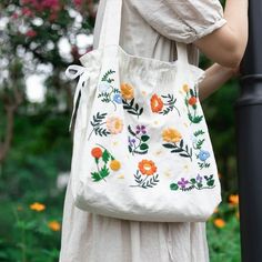 a woman wearing a white dress and carrying a floral embroidered handbag on her shoulder