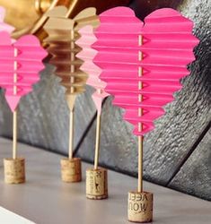 pink heart shaped paper lanterns are lined up with corks to match the color scheme