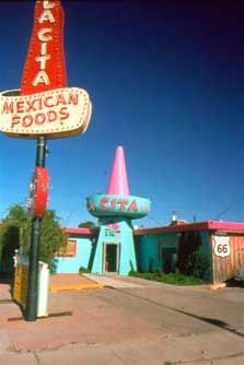 an old neon sign for mexican foods in front of a building that is blue and red