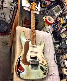 an electric guitar sitting on top of a table next to other electronics and wires in a garage