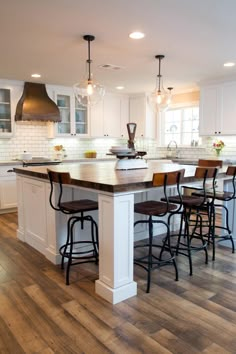 a large kitchen with an island in the middle and lots of stools around it