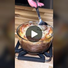 a person is cutting into a casserole dish with a knife and tongs