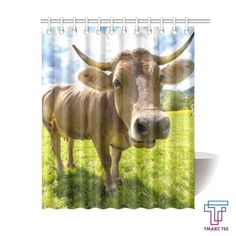 a brown cow standing on top of a lush green field next to a shower curtain