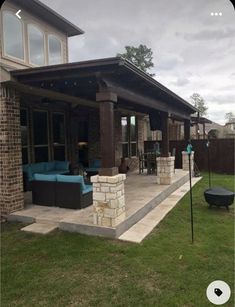 an outdoor patio with furniture on it and a grill in the back yard, surrounded by grass