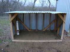 an outhouse with a metal roof in the middle of some dirt and trees behind it