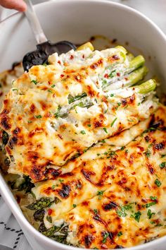 a white bowl filled with cheese and vegetables on top of a table next to utensils