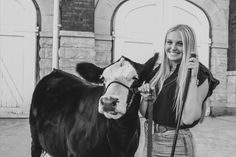 a woman standing next to a cow on a leash