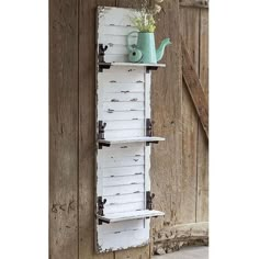 an old door is holding a shelf with flowers and a watering can