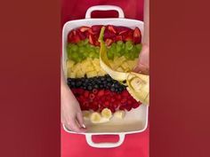 a person holding a tray full of fruit with bananas, kiwis and strawberries