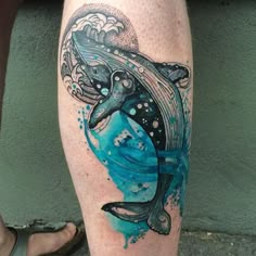 a tattoo on the leg of a person with a dolphin and waves in blue ink