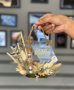 a person holding up a bottle with flowers and herbs in front of them on display