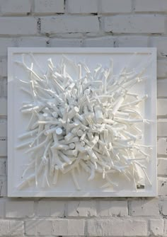 a white sculpture is mounted on a brick wall