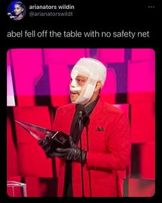 a man in a red jacket and white mask holding a microphone with the caption, abael fell off the table with no safety net