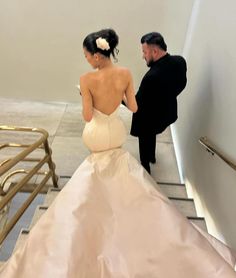 a man and woman in formal wear walking up some stairs with their back to the camera