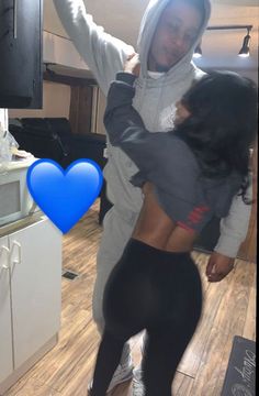 a man and woman dancing together in the kitchen with a blue heart on the floor