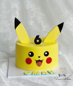 a yellow cake with a pikachu face on it's top and the number six