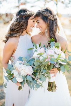 two beautiful women standing next to each other holding bouquets