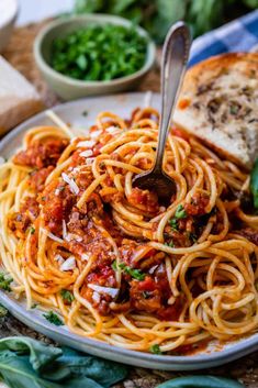 a plate of spaghetti with meat sauce and bread on the side, ready to be eaten