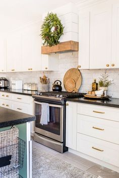 a kitchen with white cabinets and black counter tops is pictured in this image, there are wreaths on the wall above the stove