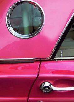 a close up of a pink car door handle with a round mirror on it's side