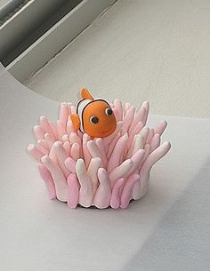 an orange and white clown fish sitting on top of pink corals in front of a window